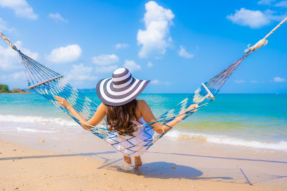 Woman with long hair relaxing in a hammock on the beach