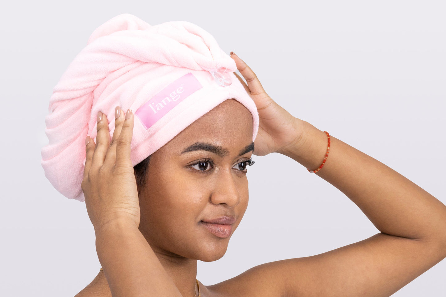 A woman positions the pink, microfiber hair wrap on her head so you can see what it looks like.